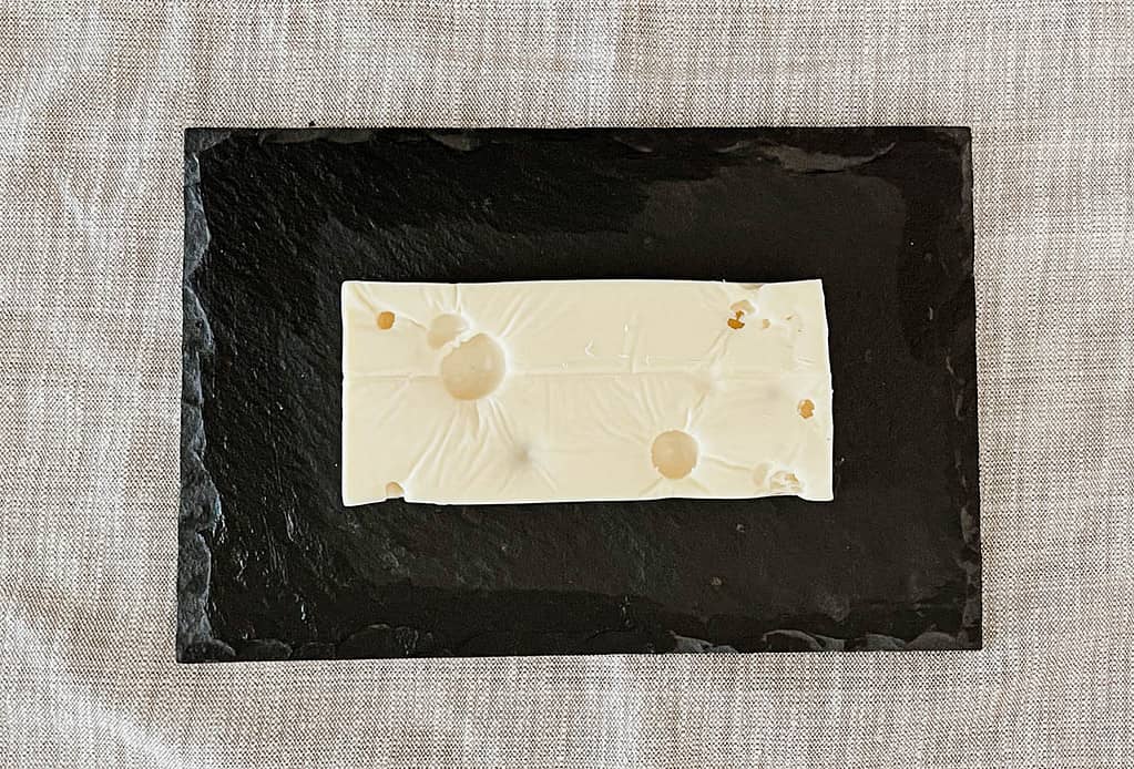 Rectangular block of swiss cheese sitting on black slate