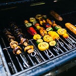Skewers of grilles meats and vegatobles roasting on a grill with skewers.