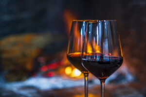 Pair of red wine glasses in front of the fireplace