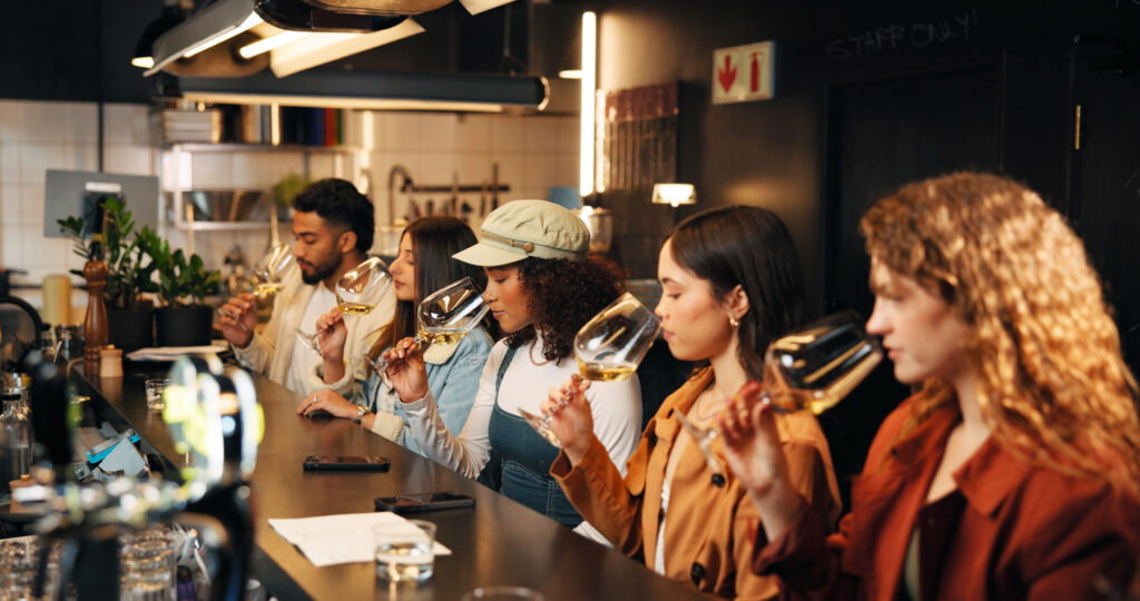 Restaurant, friends and smell glass at wine tasting for experience, flavor preparation and bonding. Night, people and alcohol aroma at pub venue for quality testing, weekend break or social gathering