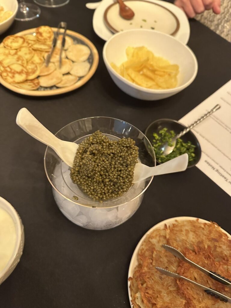 Black Sturgeon Caviar surrounded by blinis rosti, hers and potato chips