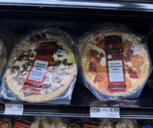two pizzas on a grocery store shelf. Mushroom on the left and peperoni on the right.
