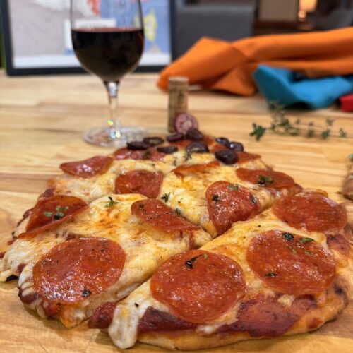 Pepperoni pizza with a glass of Cabernet Sauvignon in the background