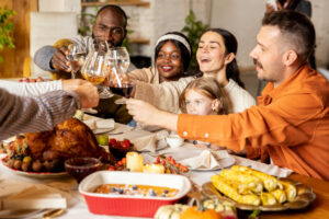 Cheers. Happy family celebrate Thanksgiving day, sitting at table with roasted turkey, holiday food, dishes. Drinking wine and congrats each other. Look happy, excited. Autumn, traditions, care, love
