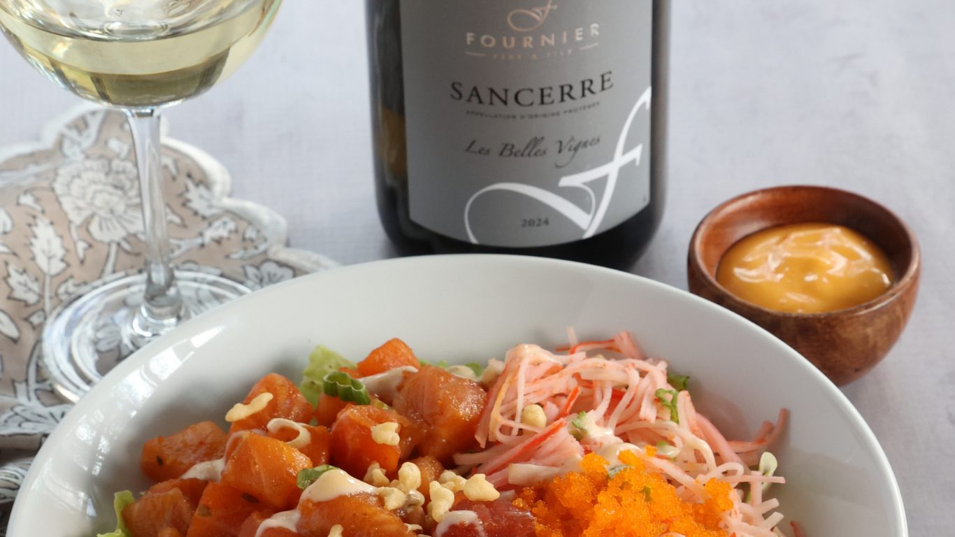 Poke Bowl + Sancerre 800×600 Raw cubes of tuna and salmon in a large white bowl, garnishes of slivered crab, lettuce, ginger, crushed nuts and sesame
