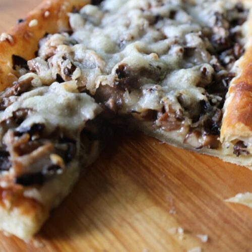 Closeup shot of flaky puff pastry covered in roasted mushrooms and gruyere cheese