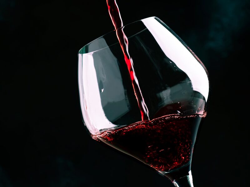 Swirling a glass of Pinot Noir against black backgroupd - backlit